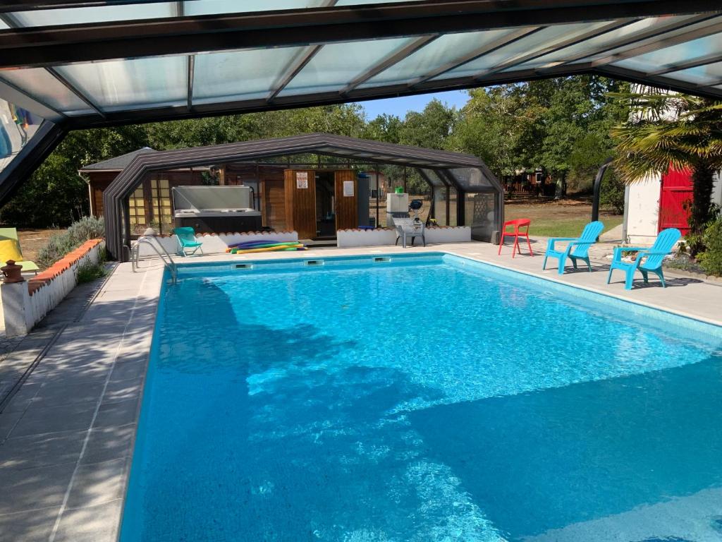 a swimming pool with a pergola and a house at Maison d'Hôtes Domaine de Labelo in Commensacq