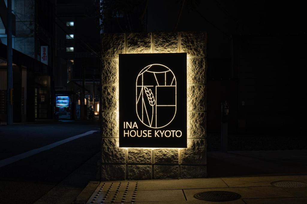 a sign on the side of a building at night at INA HOUSE Nijojo in Kyoto