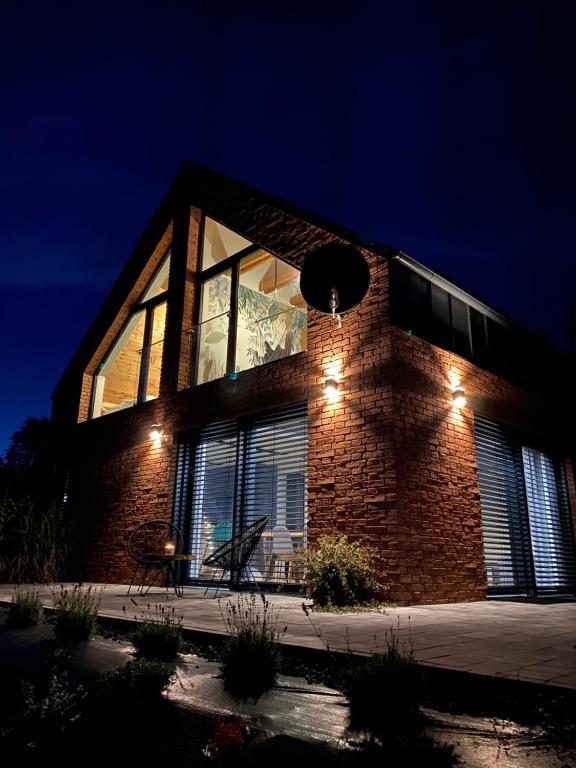 a brick building with a large window at night at Dom z balią na Kaszubach-Widokova in Borucino