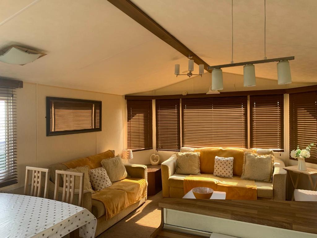 een woonkamer met een bank en een tafel bij Thornwick Bay Haven Site-Large Homely Static Caravan, Sun, Sea And Sand (SEA VEIWS , LIGHTHOUSE VEIWS) in Flamborough
