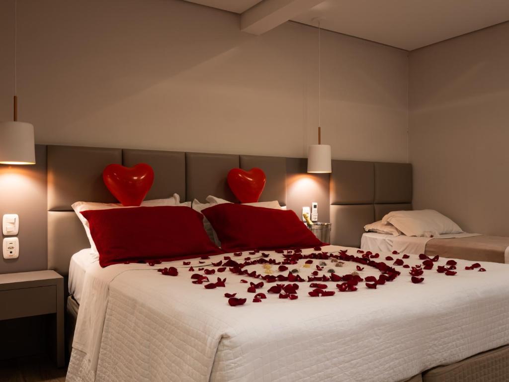 - une chambre avec 2 lits avec des cœurs rouges sur le lit dans l'établissement Alameda Alegra Hotel, à Gramado