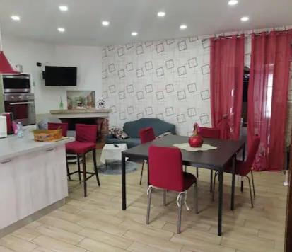 cocina y comedor con sillas rojas y mesa en Piano terra casa intera (no smoking!!!!), en Qualiano