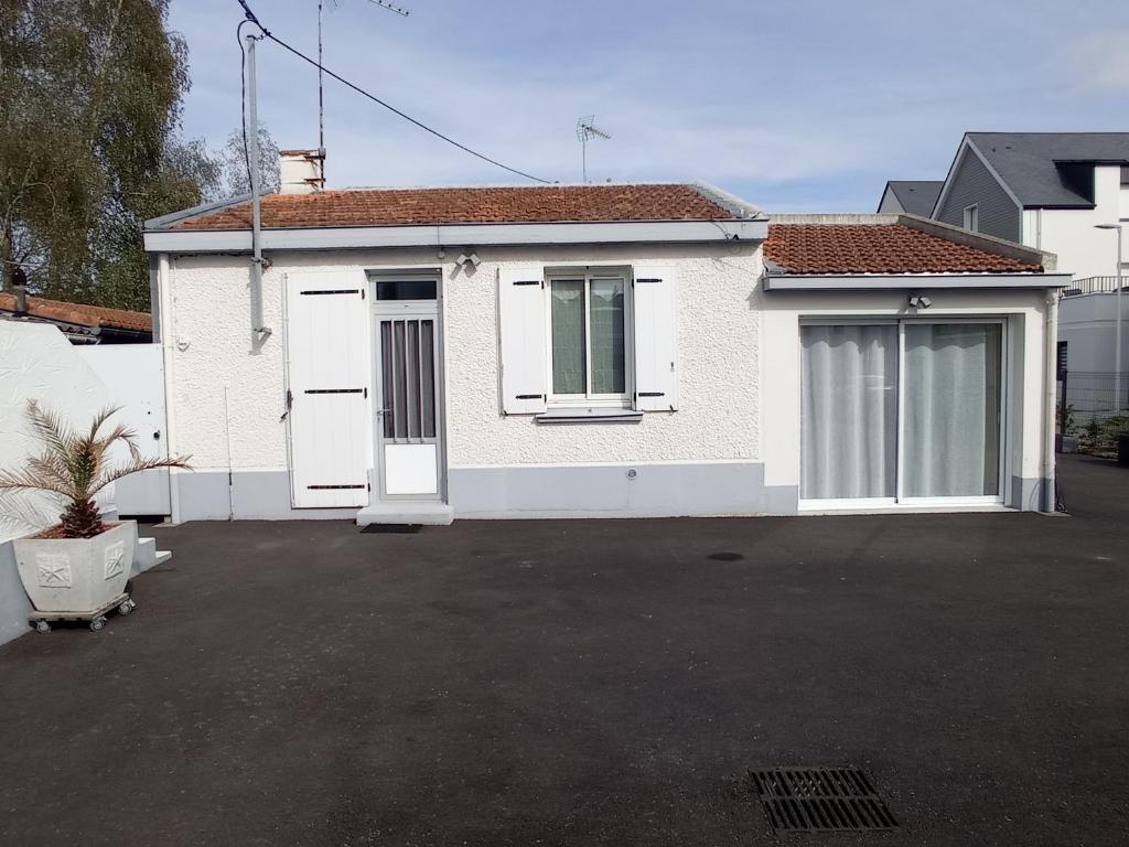 une maison blanche avec des portes blanches dans un parking dans l'établissement Résidence Floria, à La Baule