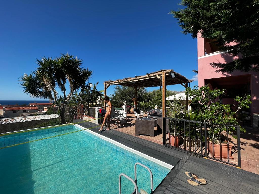 a woman is standing next to a swimming pool at Villetta dei Tramonti in Trappeto