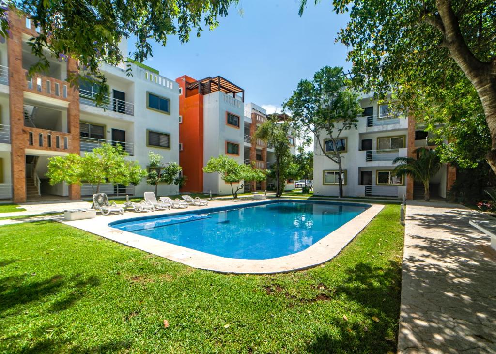 een zwembad in het midden van een tuin met gebouwen bij Cancun Airport Condo Hotel Apartment with pool and security in Cancun