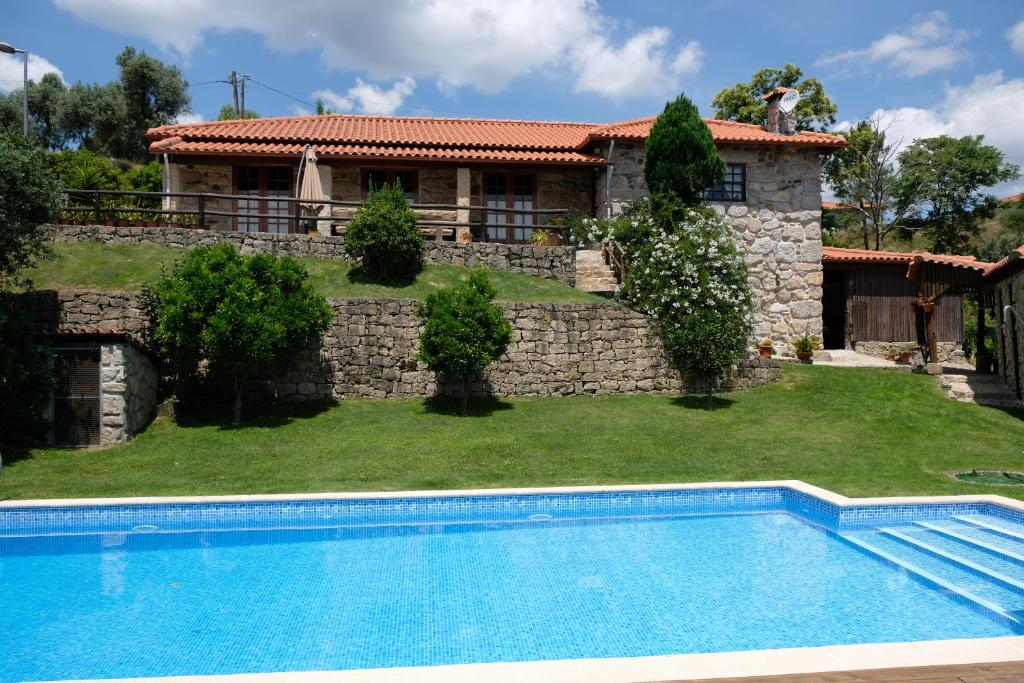 a villa with a swimming pool in front of a house at Casa das Andorinhas in Celorico de Basto