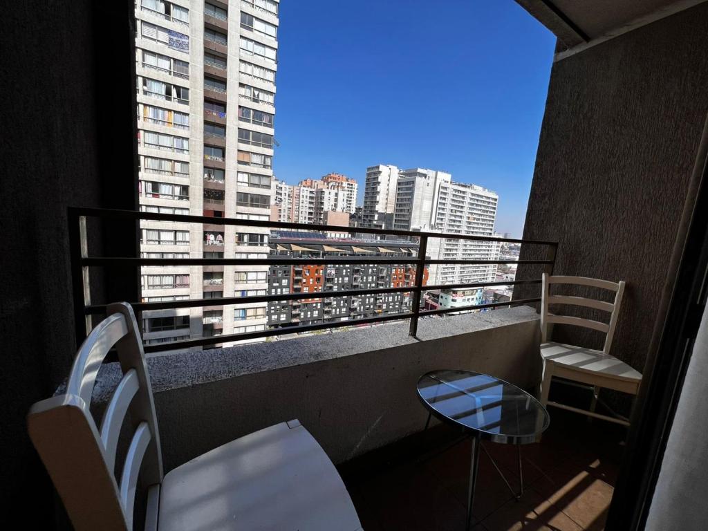a balcony with two chairs and a view of a city at Apartamentos Bulnes in Santiago