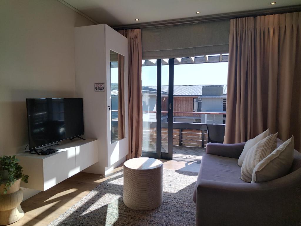 a living room with a couch and a television at The Rex Studio Apartment in Knysna