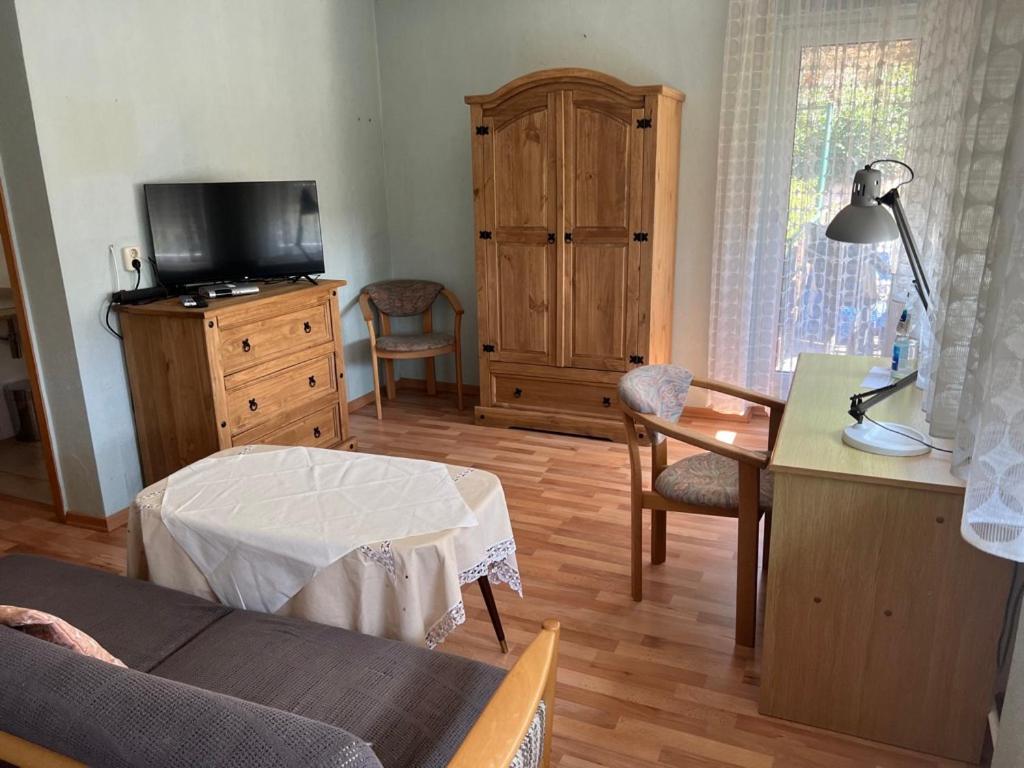 a living room with a couch and a table and a tv at Pension Klaus in Bad Salzschlirf
