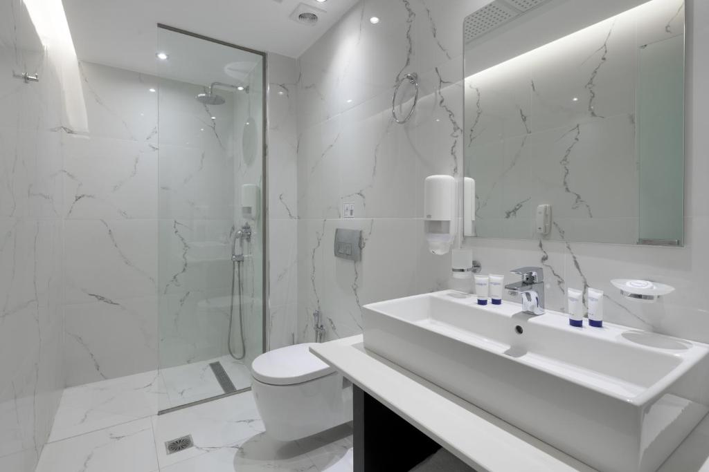 a white bathroom with a sink and a shower at Oceanis Park Hotel in Ixia