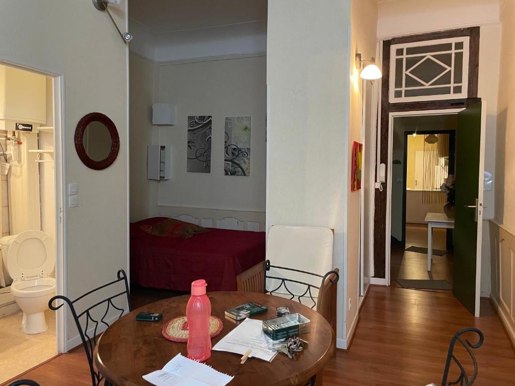 een woonkamer met een tafel en een kamer met een slaapkamer bij Studio N°1 au coeur de Bagnères de Bigorre in Bagnères-de-Bigorre