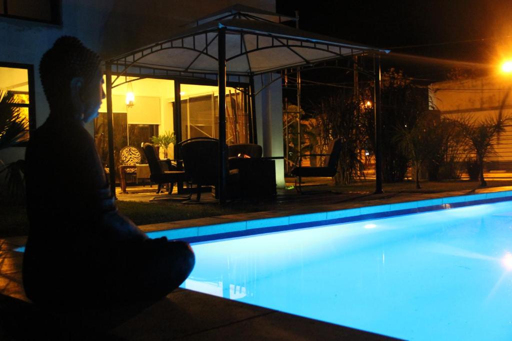 a man sitting next to a swimming pool at night at Bali Hotel Boutique in San Gregorio de Polanco