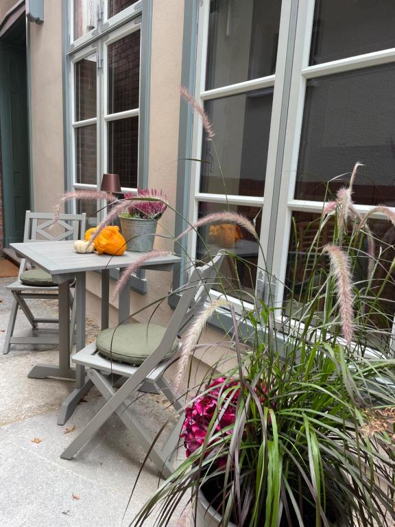 a patio with a table and chairs and plants at Warnemünde: Apartment KAJÜTE - nur 3 Gehminuten zum Strand in Warnemünde