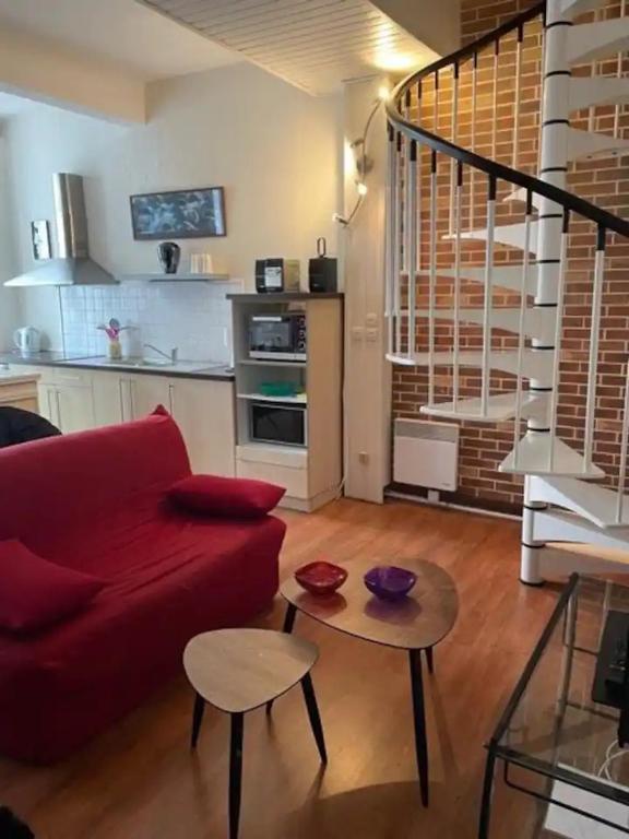 un salon avec un canapé rouge et une table dans l'établissement DUPLEX N°3 AU COEUR DE BAGNERES DE BIGORRE, à Bagnères-de-Bigorre