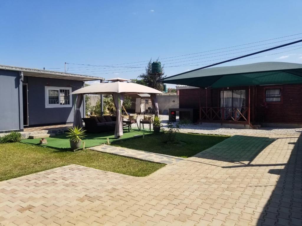 a patio with an umbrella and a house at Samkab Legacy & Comfort in Lusaka
