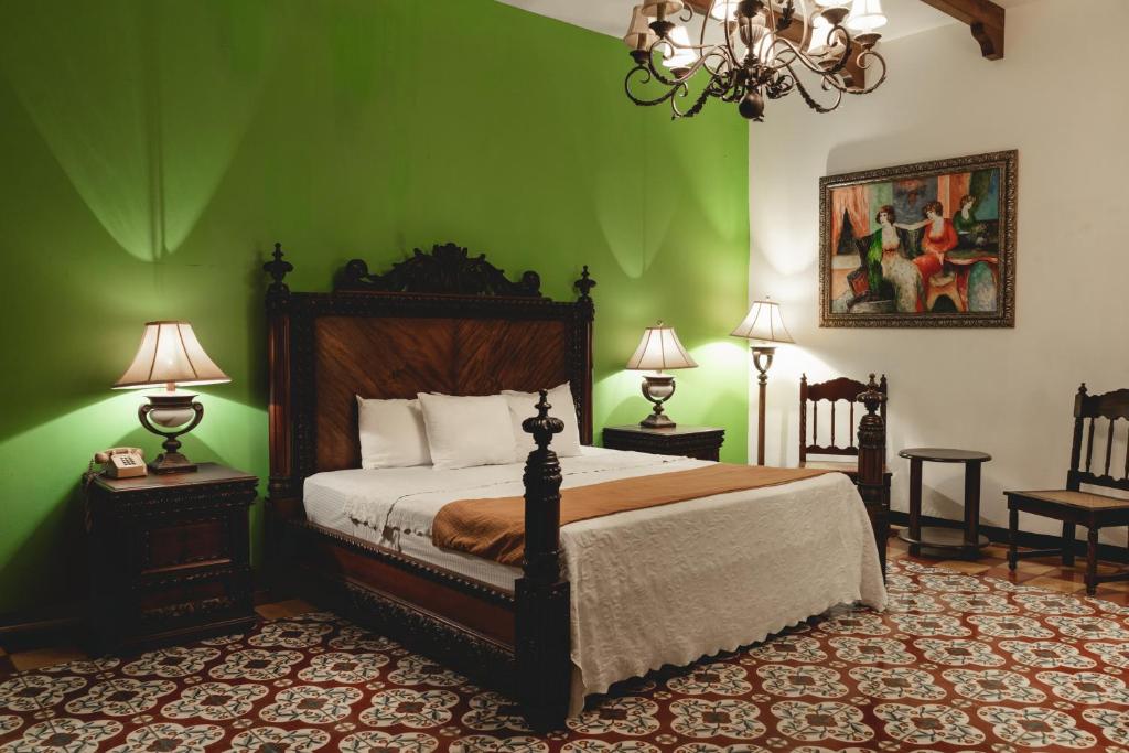 een slaapkamer met een bed met groene muren en een kroonluchter bij Hotel & Restaurante La Gran Francia in Granada