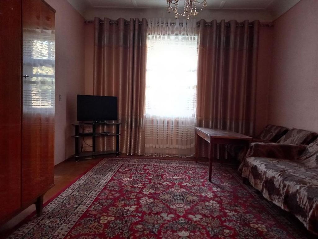 uma sala de estar com um sofá e uma televisão em Place to stay em Samarkand
