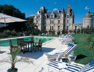 a large building with a table and chairs in front of a pool at Château de la Tremblaye in Cholet