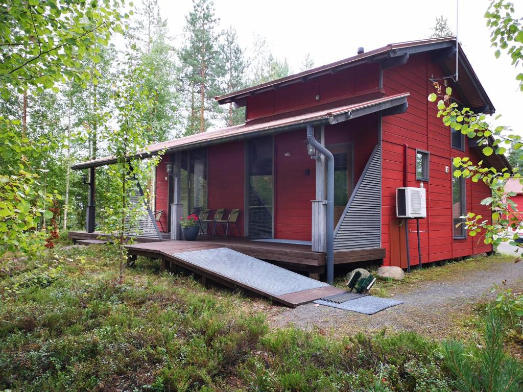 a red cabin with a porch in the woods at Loma-asunto Ahven, Kalajärvi, Maatilamatkailu Ilomäen mökit in Seinäjoki