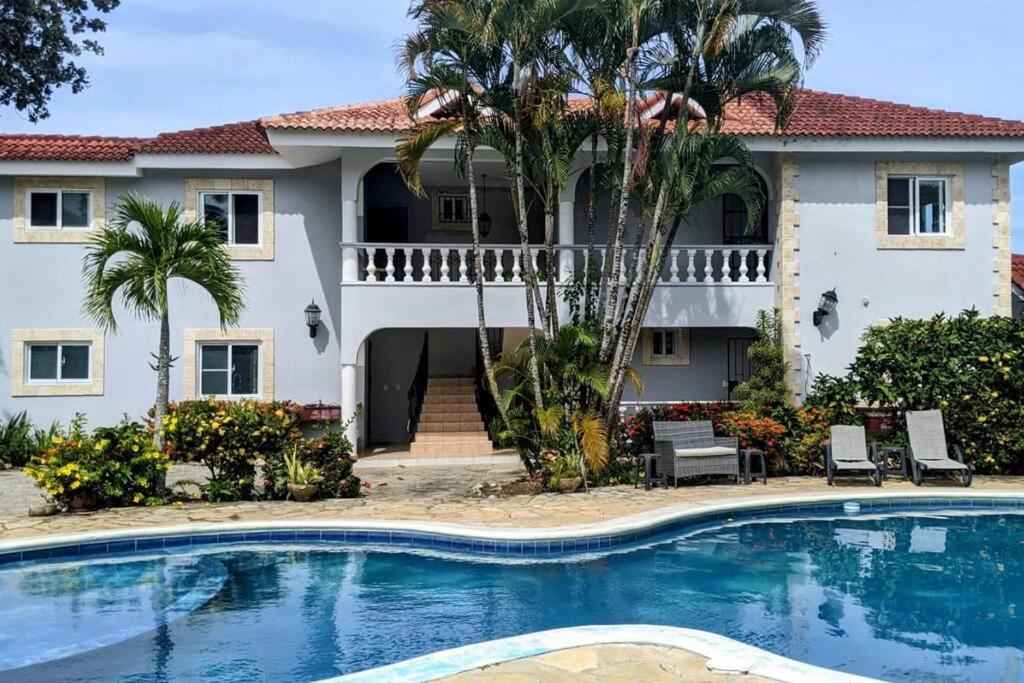 a house with a swimming pool in front of a house at Lovely 1-Bedroom Condo with Pool, walking distance to the beach in Sosúa