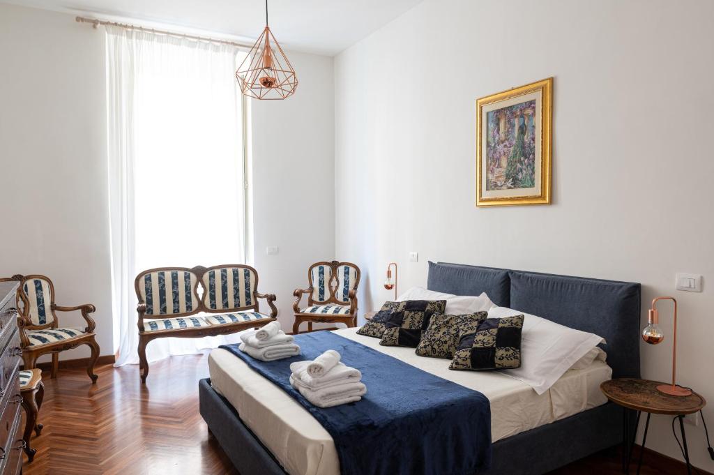 a bedroom with a bed with blue and white sheets and chairs at TimeRoma in Rome
