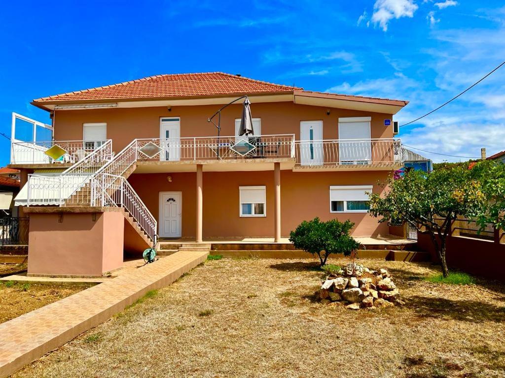 a large house with a balcony and a yard at Apartmani Dubravka in Bibinje