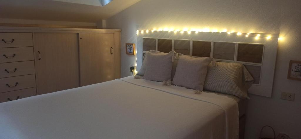 een slaapkamer met een groot wit bed met verlichting bij Ático acogedor en casco antiguo in Cangas de Morrazo