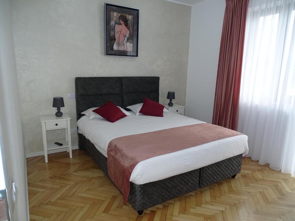 um quarto com uma cama grande e almofadas vermelhas em Water Lily Apartment Studio 2 free parking- self check-in em Oradea