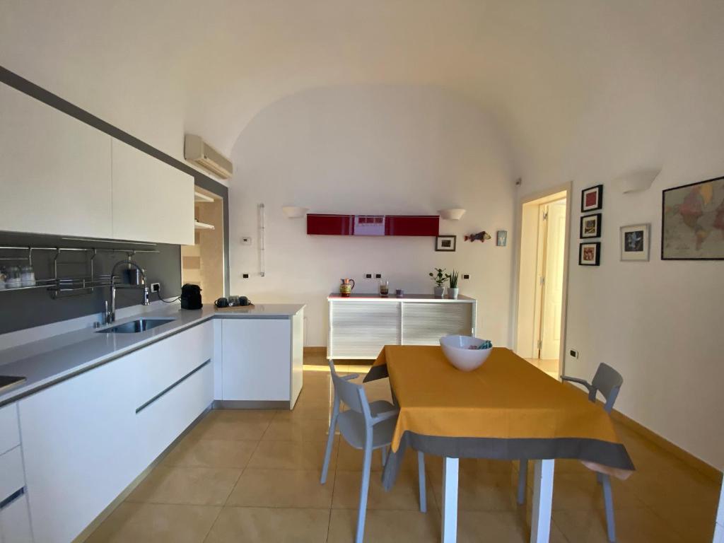 eine Küche mit einem Tisch und eine Küche mit weißen Schränken in der Unterkunft Casa Carulli49 in Bari