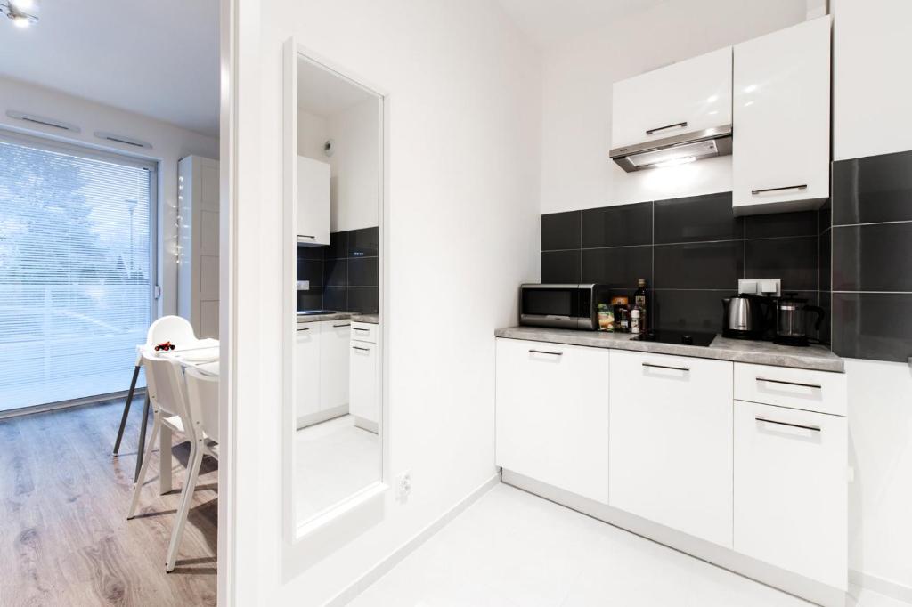 cocina blanca con armarios blancos y mesa en Project Comfort Apartament Dywizjonu 303 175/8 Warszawa, en Varsovia