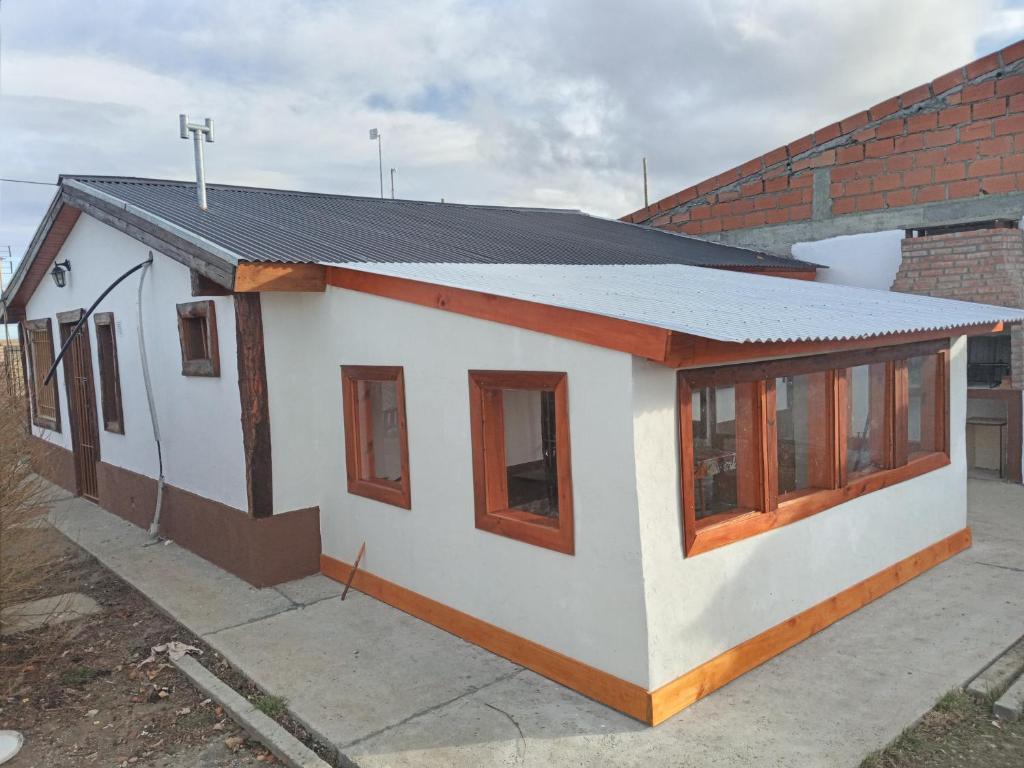 una pequeña casa blanca con techo negro en Mi Refugio en Río Gallegos