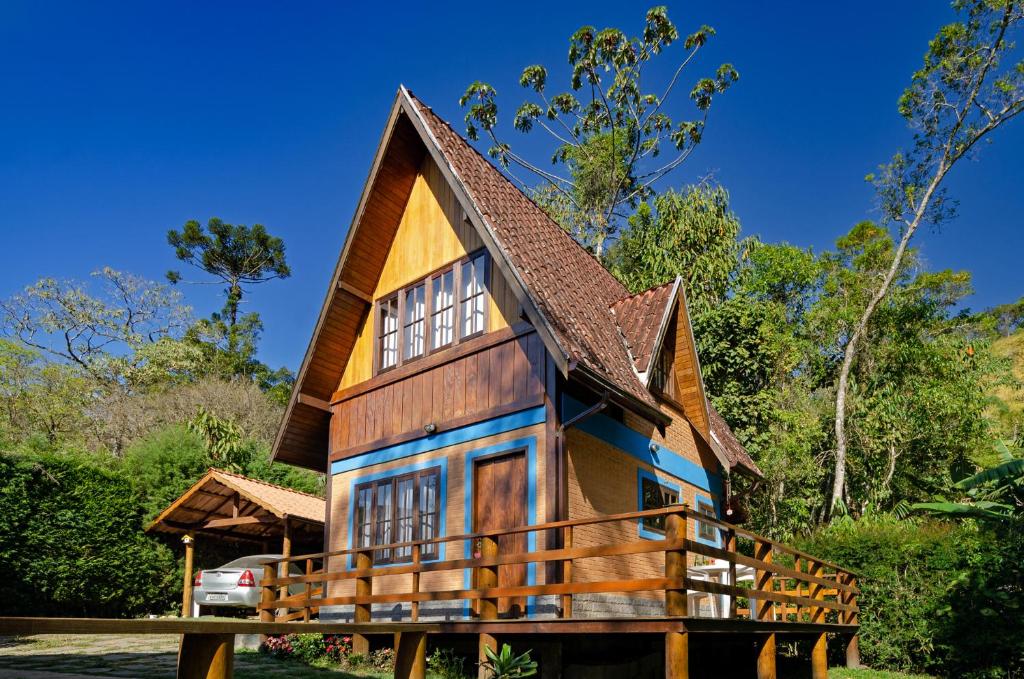 una casa con techo de gambrel sobre una viga de madera en Chalé Pasárgada - Um pedacinho do paraíso na serra, en Bocaina de Minas