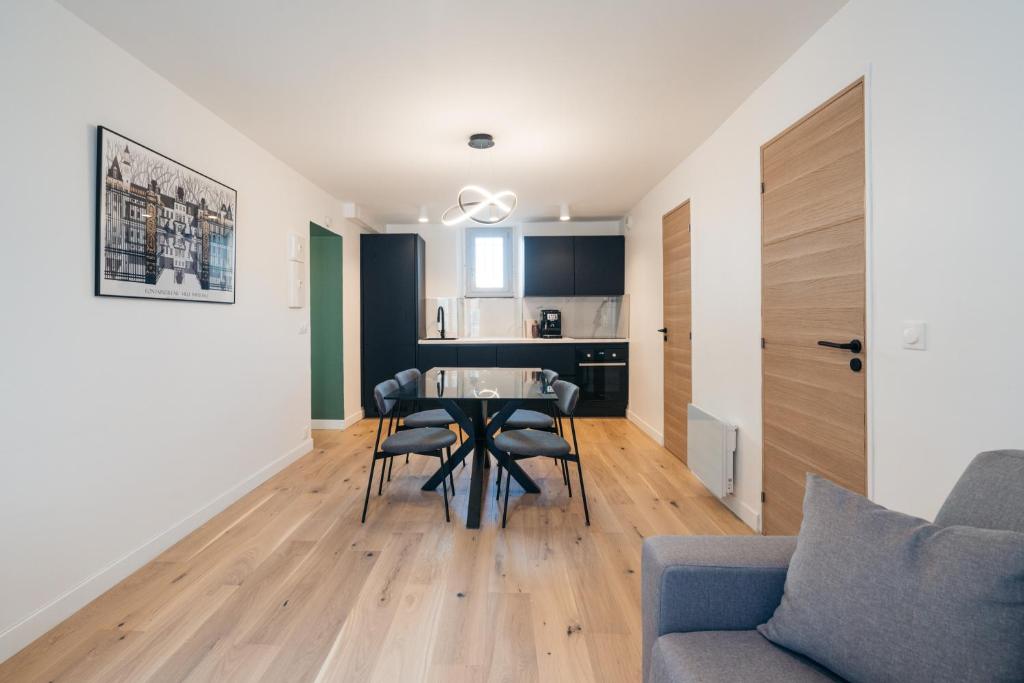 a living room with a table and chairs and a kitchen at L'Émeraude Bellifontain in Fontainebleau