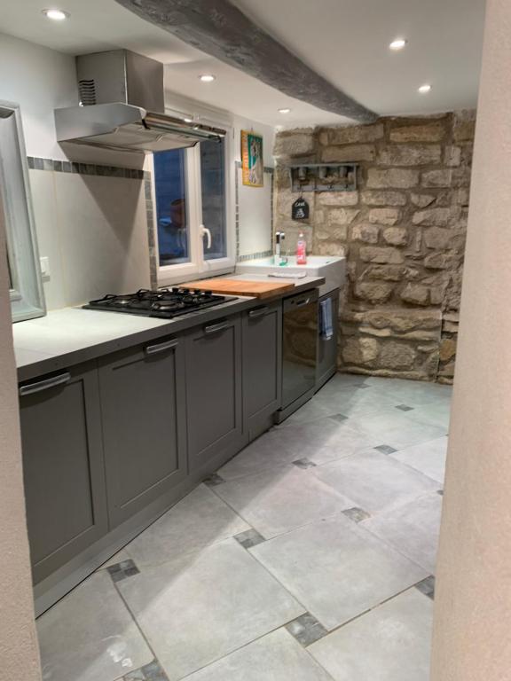 een keuken met grijze kasten en een stenen muur bij La Maison Rose in Caromb