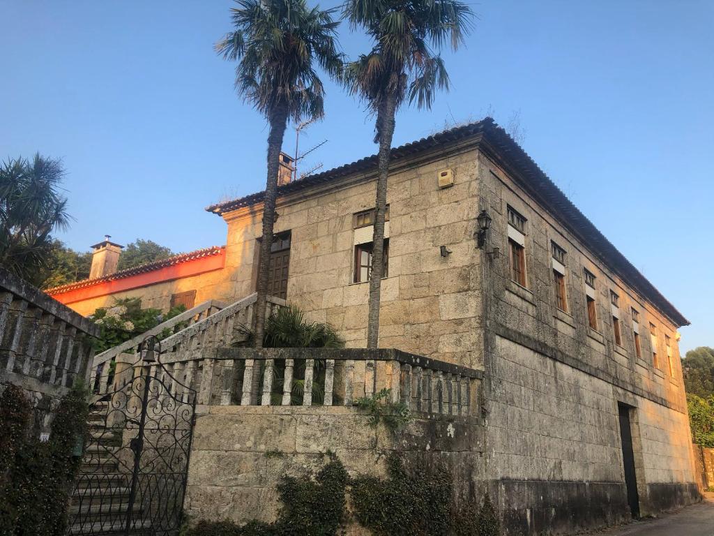 un vieux bâtiment avec deux palmiers devant lui dans l'établissement Casa Mercedes, à Ponteareas