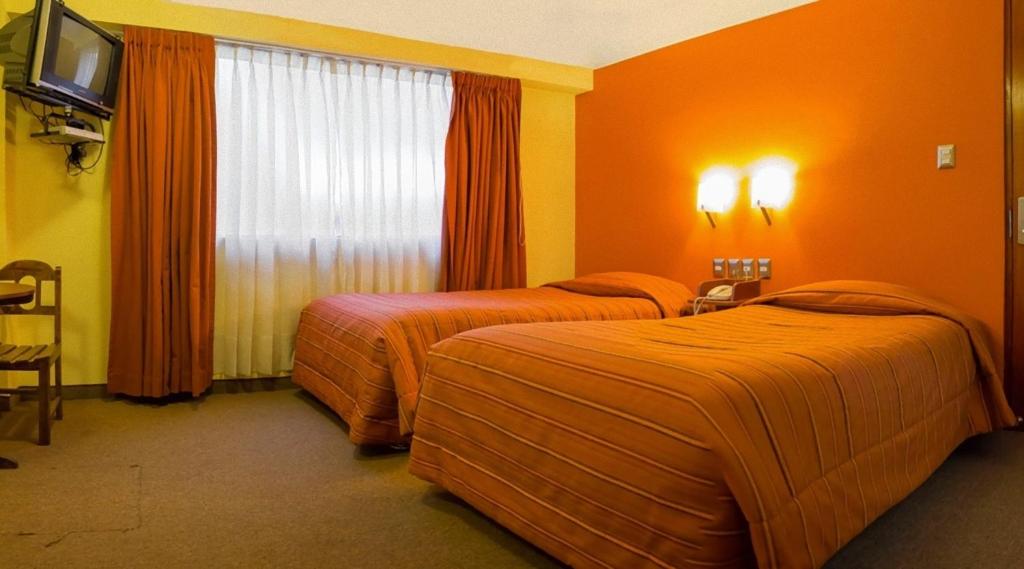 2 camas en una habitación de hotel con paredes de color naranja en Mosoq Inn en Puno