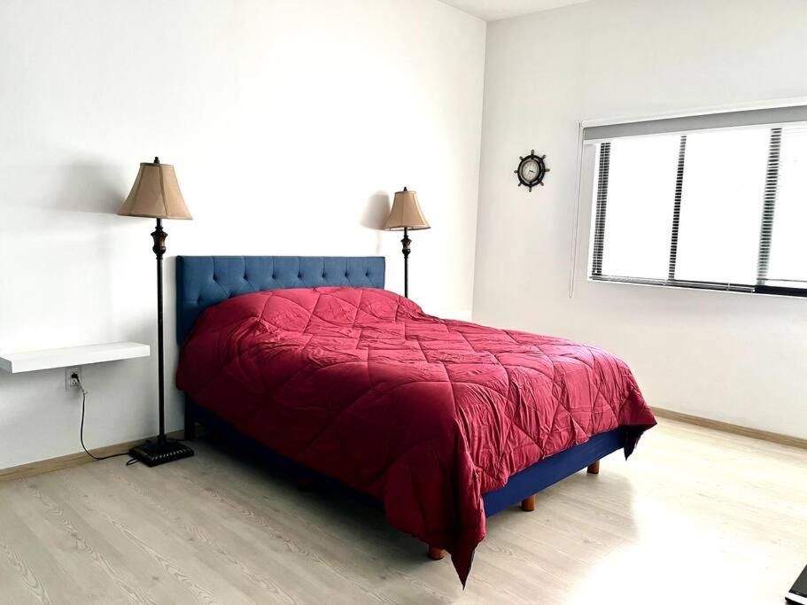 a bedroom with a bed with a red blanket and two windows at Apartment in the touristic heart of Mexico City in Mexico City
