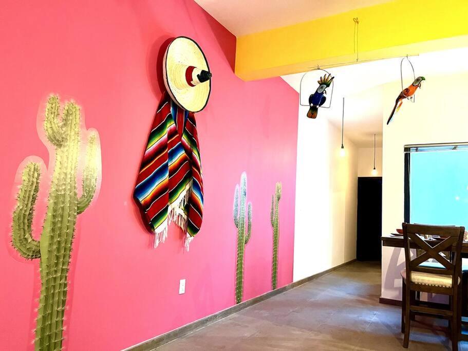 a room with a pink wall with a cactus and a clock at Apartment in the touristic heart of Mexico City in Mexico City