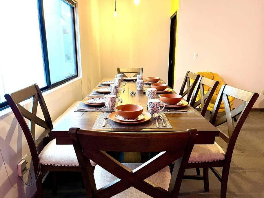 a long wooden table with chairs and plates on it at Apartment in the touristic heart of Mexico City in Mexico City
