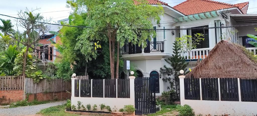 a white house with a gate and a fence at Secret Garden Homestay in Siem Reap