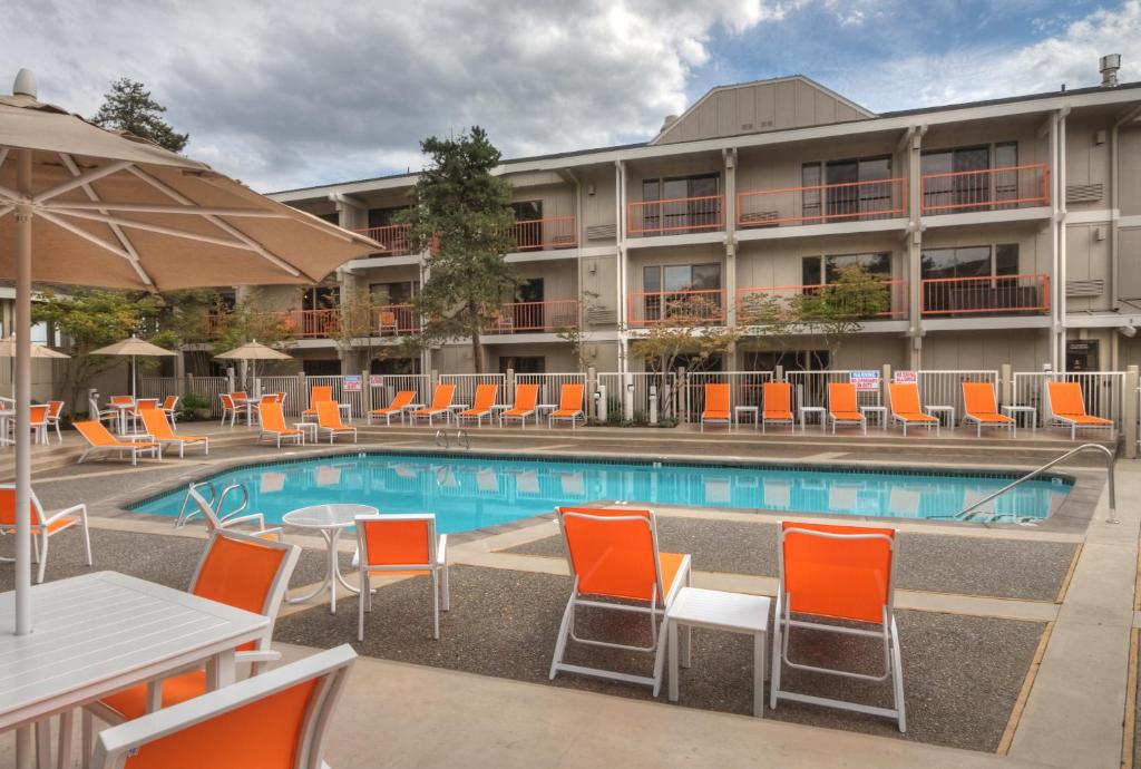 einen Pool in einem Hotel mit orangefarbenen Stühlen und Tischen in der Unterkunft Ashland Hills Hotel & Suites in Ashland