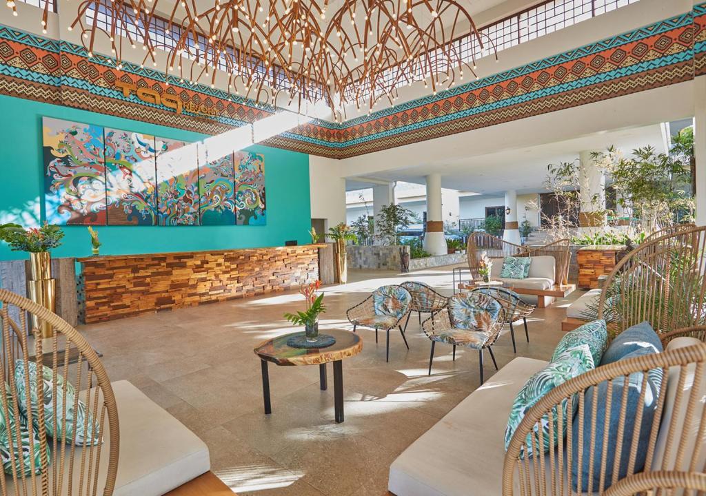 a lobby with chairs and tables and a painting on the wall at Tag Resort in Coron