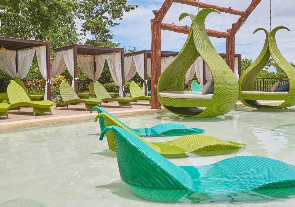 a swimming pool with green chairs and a swing at Tag Resort in Coron