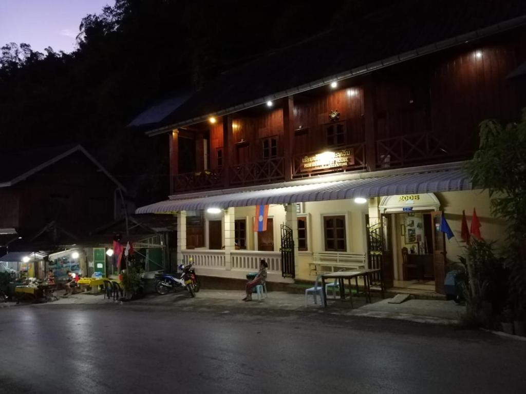 a person sitting outside of a building at night at Monsavanh Guesthouse in Pakbeng