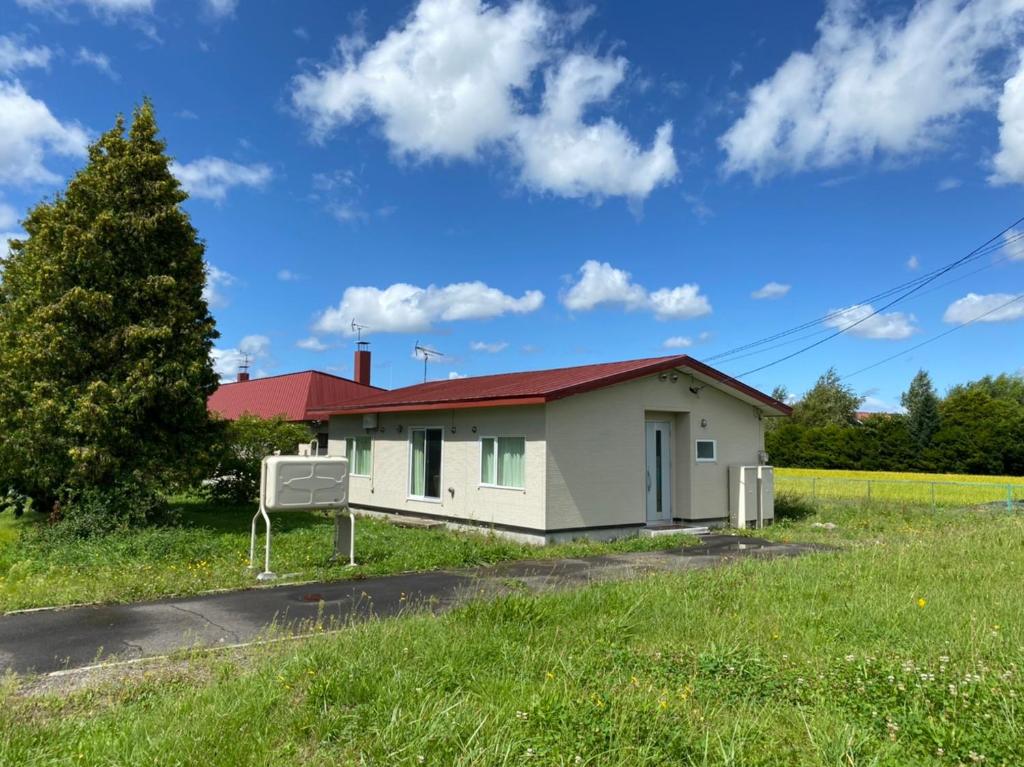 una pequeña casa blanca con techo rojo en 東神楽大学ゲストハウス, en Higashikagura