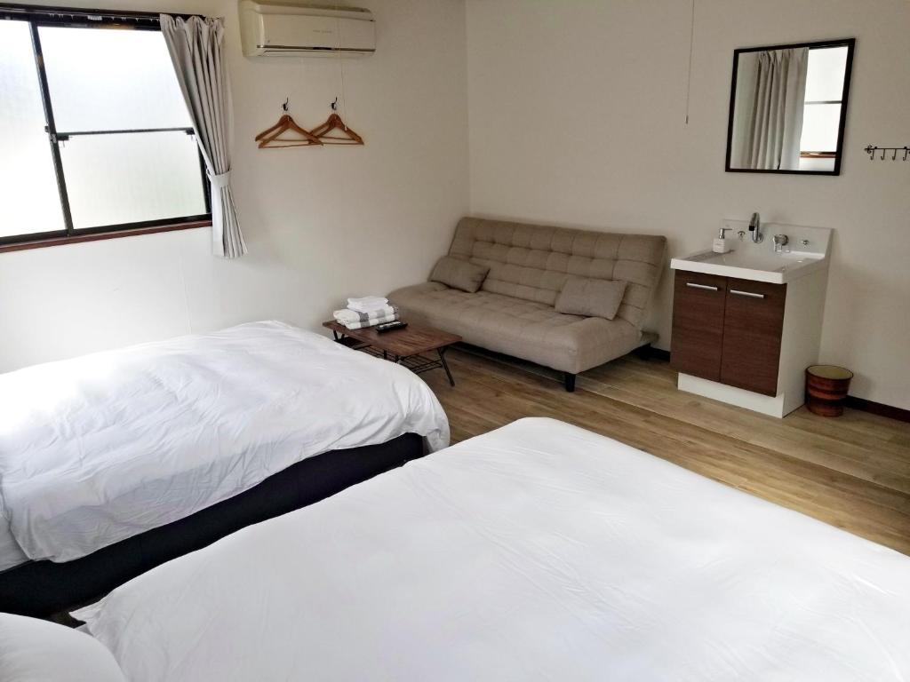 安来市にあるGuest House Tataraのベッド2台とソファが備わるホテルルームです。