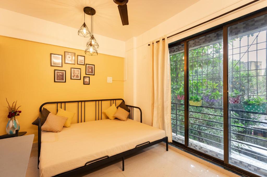 CollarCamp 1BHK Apartment في نافي مومباي: غرفة نوم بسرير ونافذة كبيرة