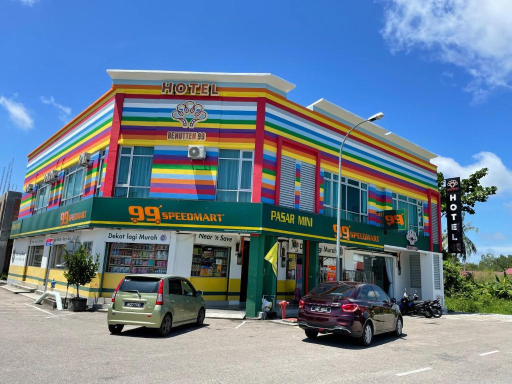 un edificio colorido con coches estacionados frente a él en BENUTTEN 99 HOTEL, en Kampong Parit Tengah
