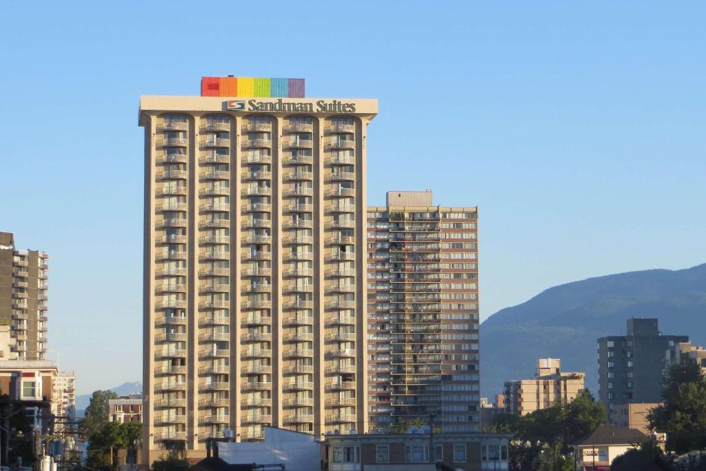 un grand bâtiment avec un panneau en haut dans l'établissement Sandman Suites Vancouver on Davie, à Vancouver