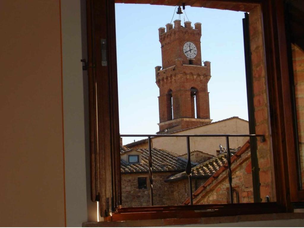 una ventana con vistas a una torre del reloj en La Corte Antica, en Pienza